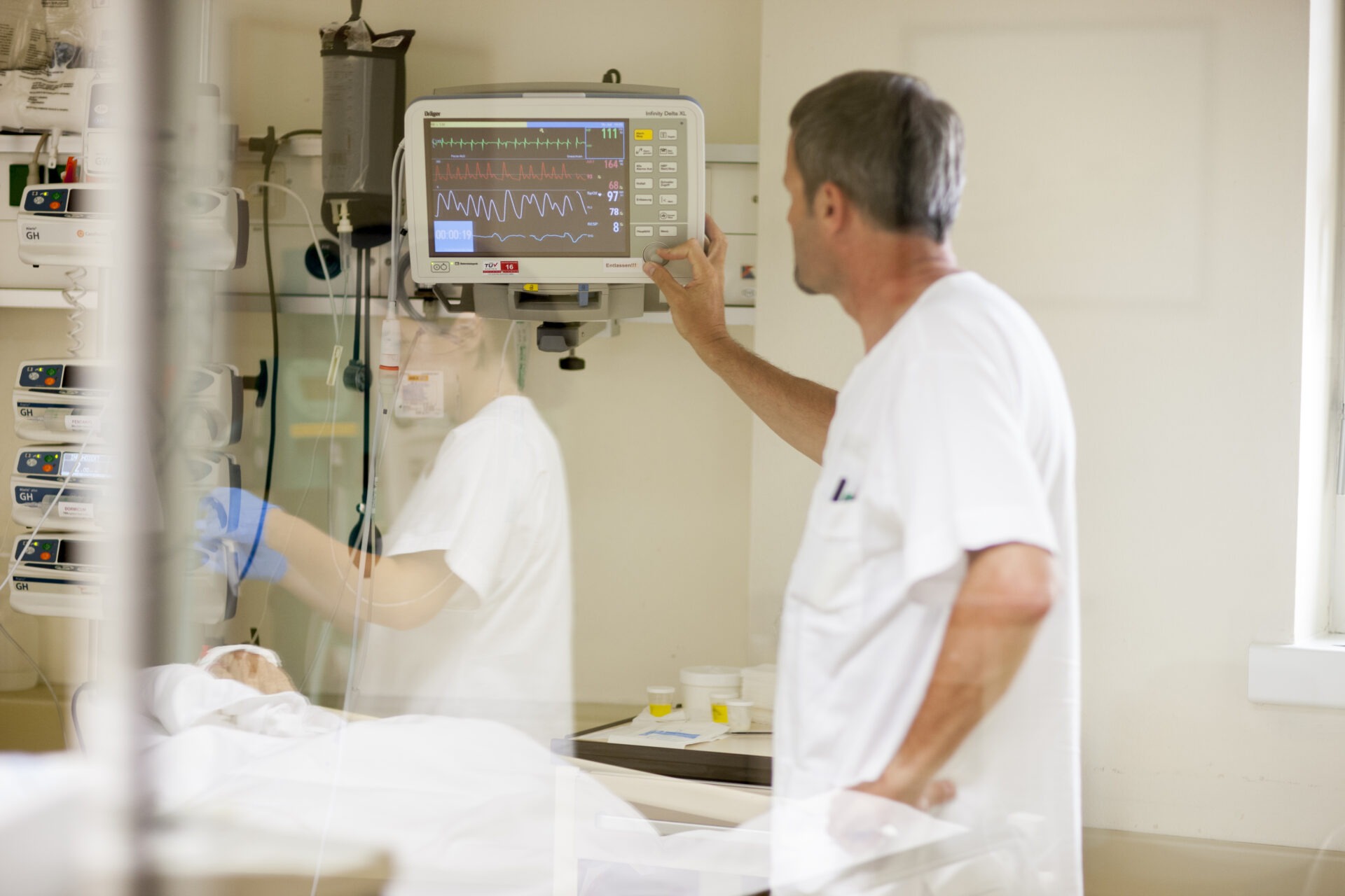 Die DGKP sieht sich die Zahlen am Monitor an, welcher beim Patienten angeschlossen ist