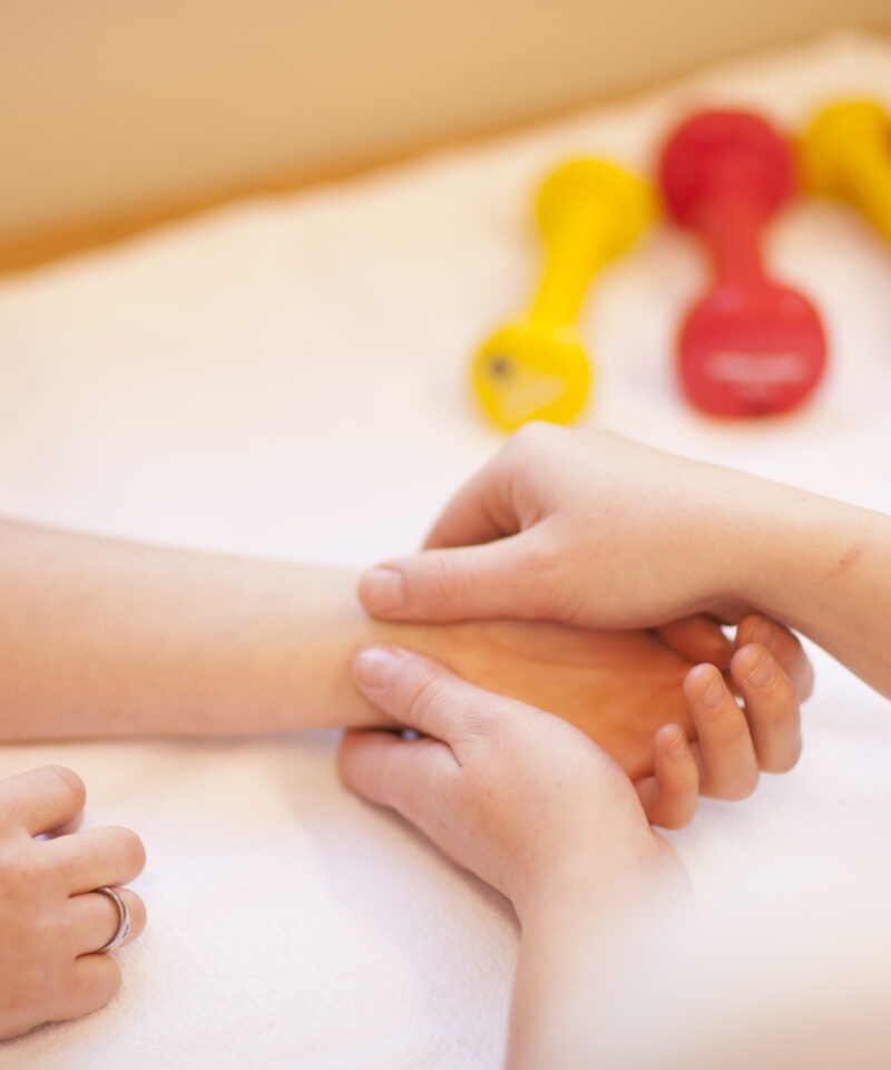 Die Ergotherapeutin massiert die Hand eines Patienten