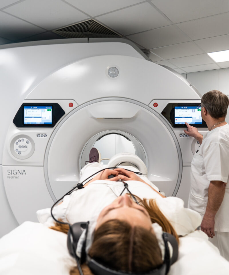 Der Radiotechnologe stellt die letzten Einstellungen beim CT-Gerät ein, bevor die Patientin hineingefahren wird