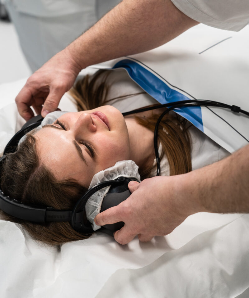 Der Radiotechnologe setzt der Patientin die Kopfhörer auf, bevor sie ins CT-Gerät kommt