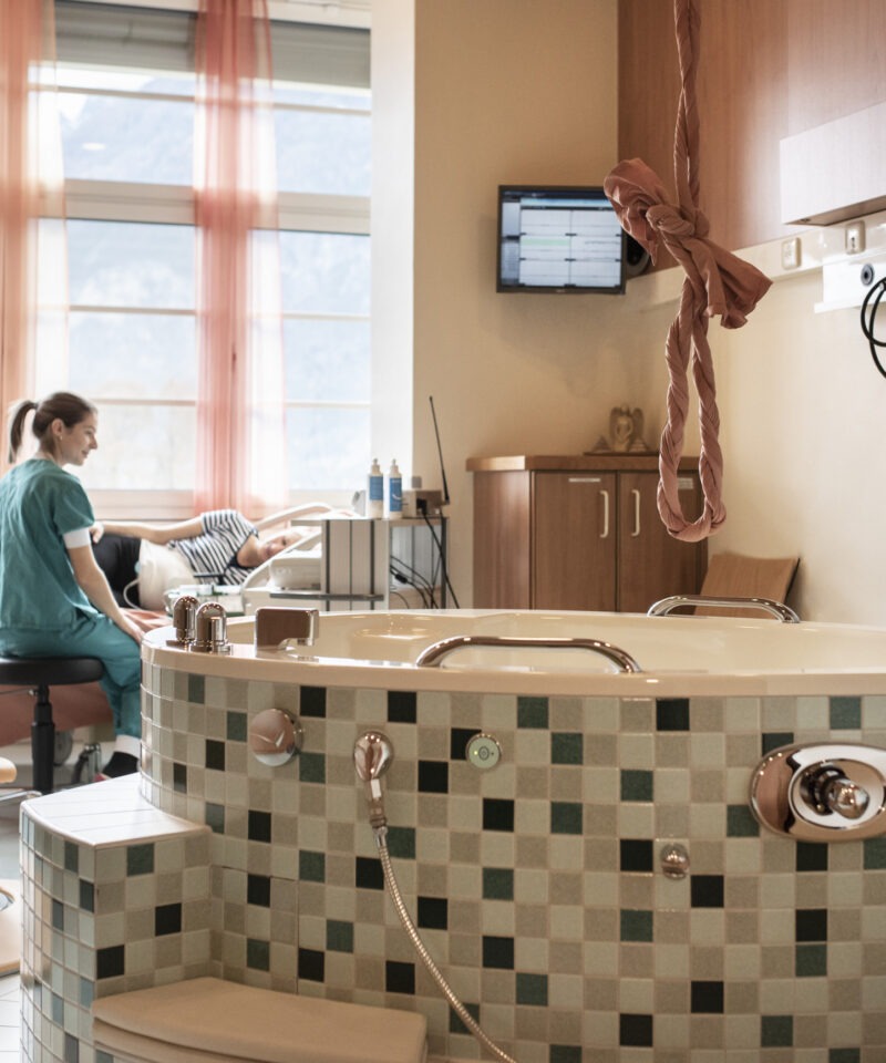 Die Hebamme macht im Wannenzimmer eine Untersuchung am Babybauch der Patientin