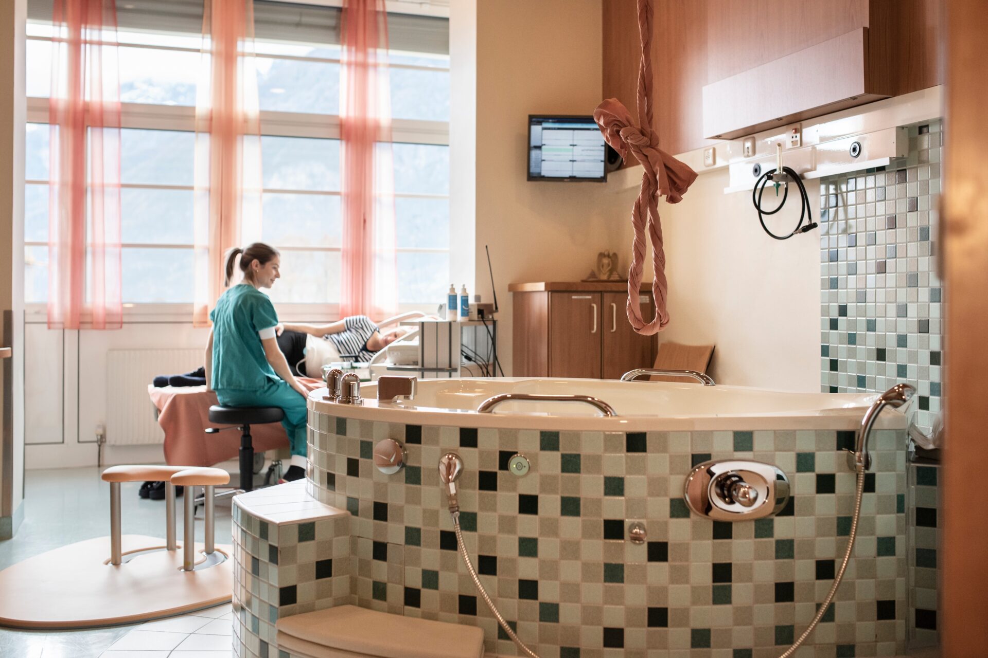 die Hebamme betreut eine schwangere Patientin im Wannenzimmer