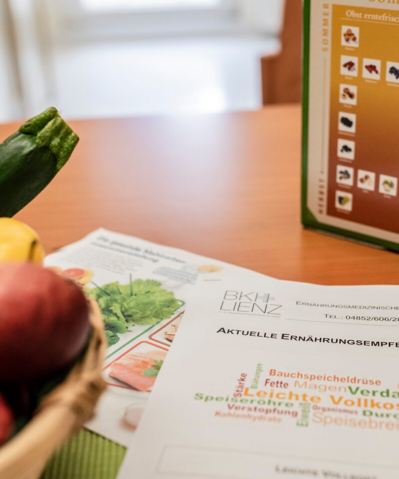 Obst sowie eine Anleitung zur gesunden Ernährung liegen am Tisch der Diätologie