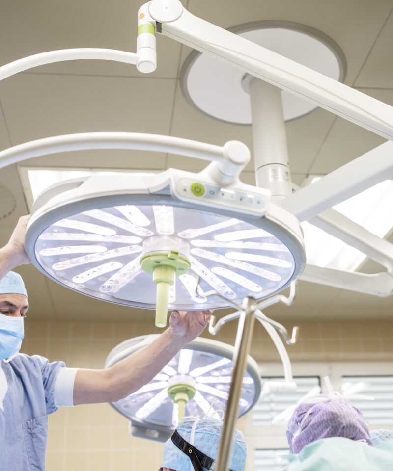 eine OP-Assistenz richtet die OP-Lampe im OP-Saal ein