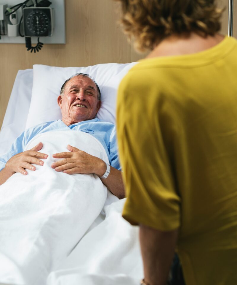 ein Angehöriger besucht einen älteren Patienten im Patientenzimmer