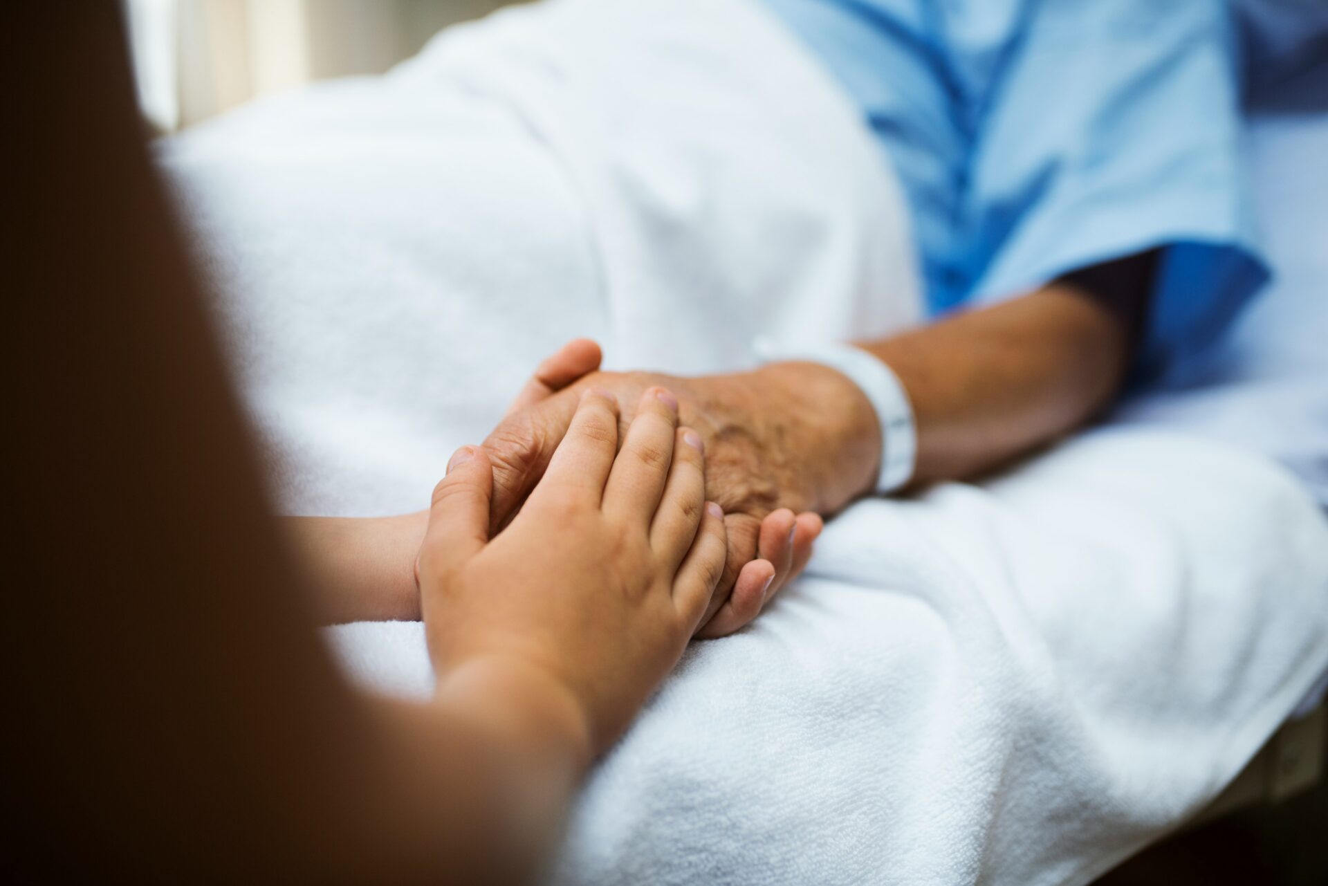 ein Angehöriger hält die Hand eines Patienten
