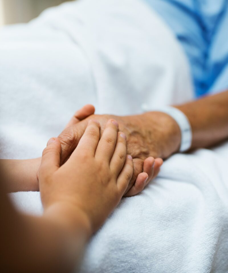 ein Angehöriger hält die Hand eines Patienten