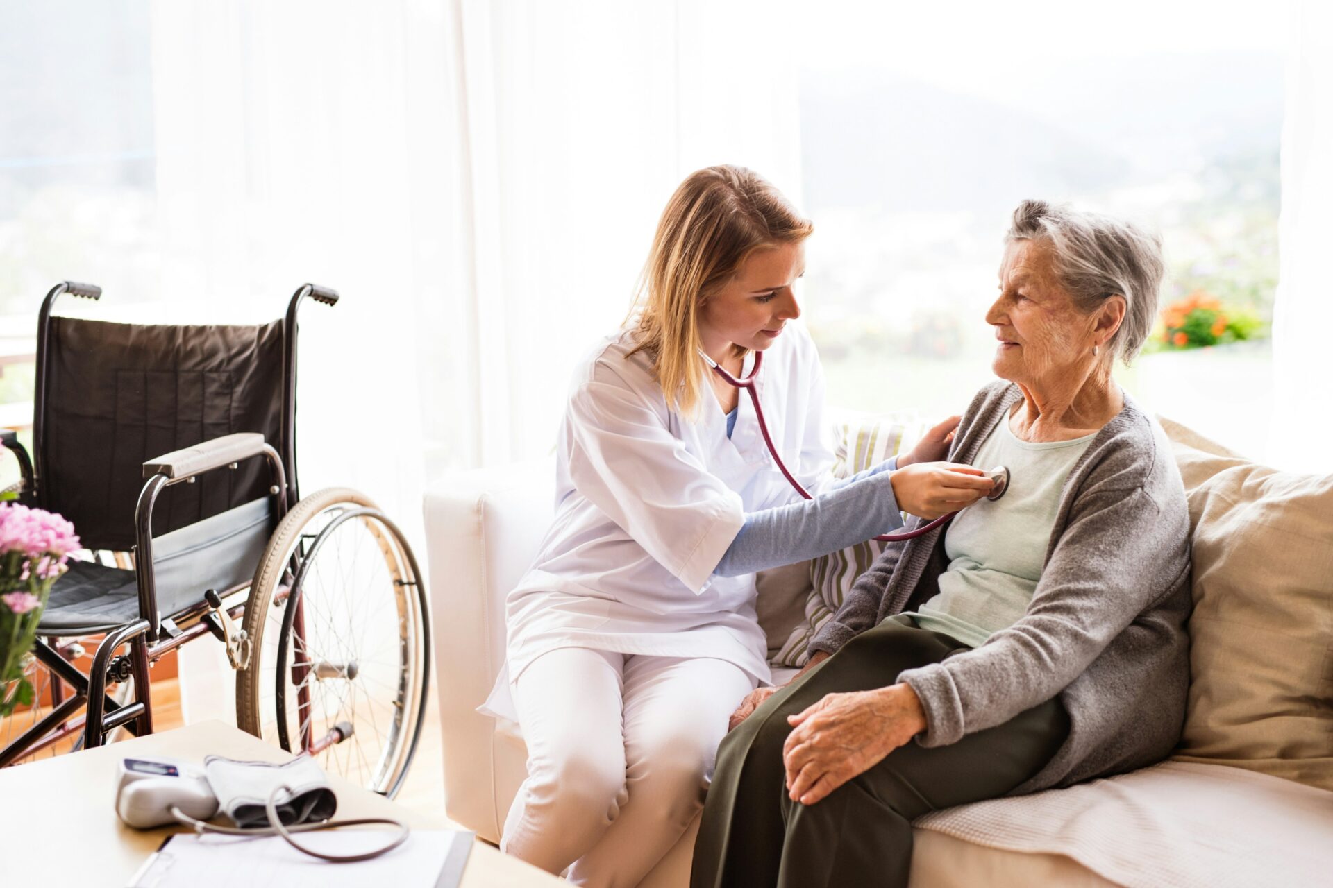 eine diplomierte Pflegekraft misst den Blutdruck eines älteren Patienten mittels Stethoskop